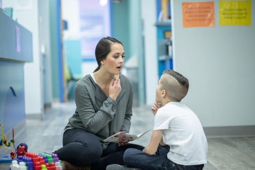 Female NDIS speech therapist works with young boy, speech therapy for children session