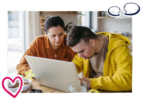 A young man being assisted using a laptop by a woman A young man being assisted using a laptop by a woman