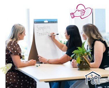 Three women drawing on a large notepad as a group