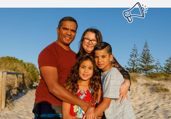 An Aboriginal family on a beach, smiling to camera